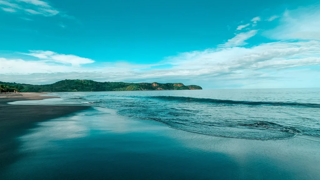 Waves washing onto a Guanacaste beach beneath a blue sky